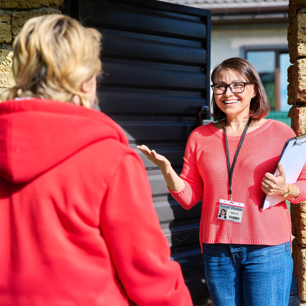 Social worker smiling and speaking with a community member during a home visit
