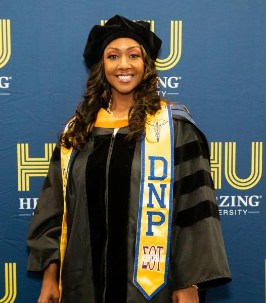 Herzing University Doctor of Nursing graduate in cap and gown at graduation event.